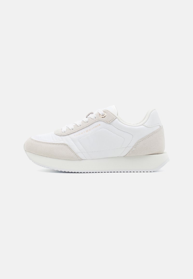 Baskets de sport blanches avec accents en daim beige, dessus synthétique, bout rond, lacets plats et semelle en caoutchouc texturée. Présente un détail de logo.