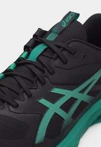 Μαύρο και τιρκουάζ αθλητικό παπούτσι Asics με μαύρα κορδόνια, άνω μέρος από δίχτυ και εμφανές τιρκουάζ λογότυπο στο πλάι.