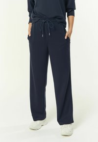 Marineblaue leichte Jogginghosen mit elastischem Bund, Kordelzugverschluss und Seitentaschen, die einen lässigen Schnitt und eine glatte Textur bieten.