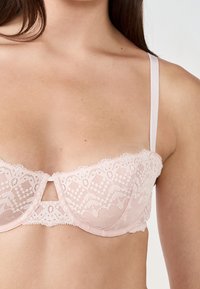 Soutien-gorge balconnet en dentelle rose pâle avec motif floral, bords délicats à volants, soutien-gorge à armatures et fines bretelles ajustables.