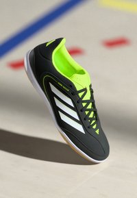 Scarpa da calcio indoor nera con accenti verde neon, strisce bianche, design con lacci, parte superiore testurizzata e suola in gomma. Presenta l'etichetta "Copa Indoor".