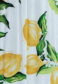 Witte stof met een citroen- en groene bladenpatroon, met een gladde textuur en levendige gele citroenen met subtiele details en accenten.
