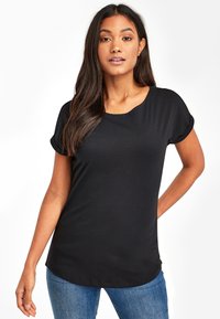 T-shirt nera a maniche corte con scollatura rotonda; tessuto morbido e liscia; orlo curvo; vestibilità casual; abbinato a jeans blu.