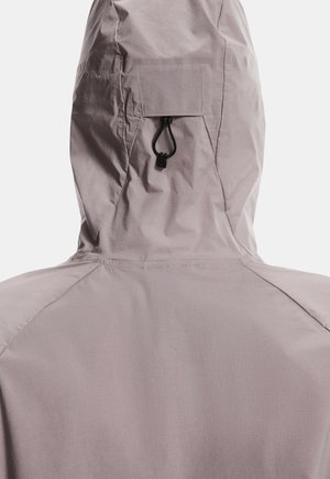 Gaiši pelēka cepure ar kapuci, kam ir auklu aizdare kakla daļā, gluda tekstūra un minimālistisks dizains bez redzamām logo zīmēm.