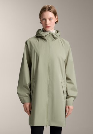 Imperméable vert clair avec capuche, fermeture éclair à l'avant et poches latérales. Offre une coupe décontractée et une texture lisse et mate.