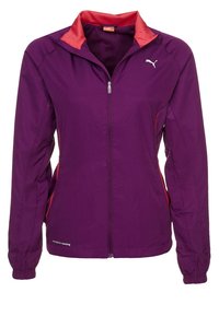 Lila idrottsjacka med dragkedja, röda kragspecifikationer, sidofickor och elastiska muddar. Lätt och ventilerande tyg.