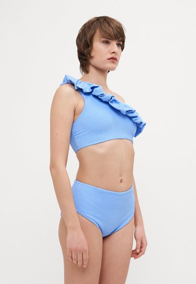 Kék textúrájú bikini szett, egy vállas top ruffle részletekkel és magas derekú alsó résszel. Simább anyag, enyhe rugalmassággal.