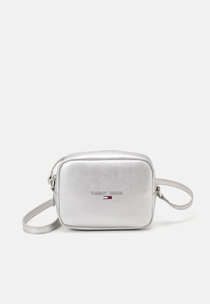 Petit sac bandoulière argenté avec sangle réglable, forme rectangulaire, et logo "Tommy Jeans" avec drapeau rouge, blanc et bleu à l'avant.