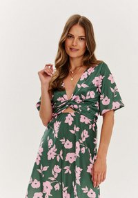 Zelené kvetinové šaty s hlbokým výstrihom do V, krátkymi rukávmi, skrúteným telom a vzorom ružových kvetov po celom obvode. Hladká, ľahká látka.