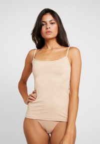 Débardeur beige à fines bretelles; design ajusté; texture lisse; associé à un bas de bikini assorti.