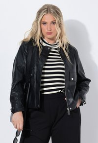 Veste en cuir noir avec col côtelé, quincaillerie argentée et poches avant, portée sur un haut à rayures noir et blanc.