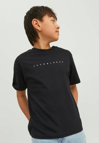 Juodas medvilnės marškinėliai su apvaliu iškirpimu ir trumpomis rankovėmis. Priekyje užrašyta "JACK & JONES" balta spalva. Paprastas dizainas.