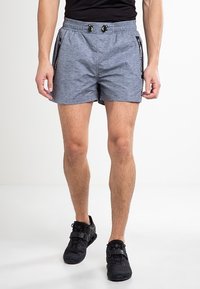 Šedé sportovní šortky s texturovanou tkaninou, elastickým pasem a nastavitelnými šňůrkami. Boční kapsy na zip s kontrastními akcenty.