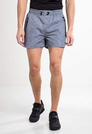 Šedé sportovní šortky s texturovanou tkaninou, elastickým pasem a nastavitelnými šňůrkami. Boční kapsy na zip s kontrastními akcenty.
