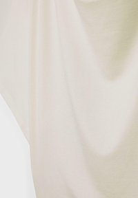 Tissu lisse de couleur crème avec des plis doux et des ombres subtiles, montrant la texture et le drapé.