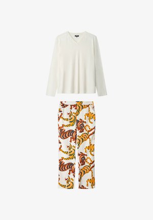 Biała bluzka z długim rękawem i dekoltem w serek w połączeniu z białymi spodniami z kolorowym nadrukiem tygrysa w odcieniach pomarańczowego, niebieskiego i żółtego.