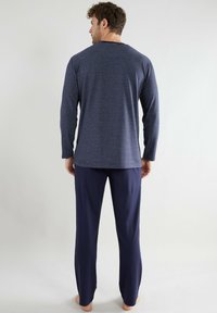 Navy striped long-sleeve top and matching pants made from soft fabric. The design features horizontal stripes and a relaxed fit.