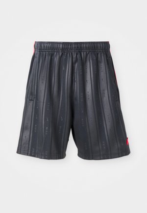Shorts de sport noirs avec des rayures verticales et de petits logos Nike répétés, dotés d'une taille élastique et de détails rouges sur le côté.