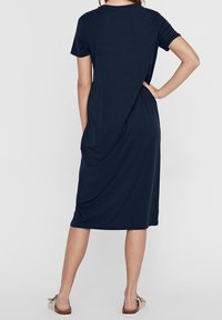 Marinblå t-shirt klänning med korta ärmar, avslappnad passform och en draperad bakdesign. Tillverkad av mjukt material med en slät textur.