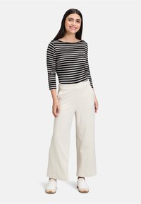 Czarno-biały pasiaste długie rękawki, luźny krój. Kremowe szerokie spodnie z plisami z przodu. Białe trampki z brązowymi akcentami.