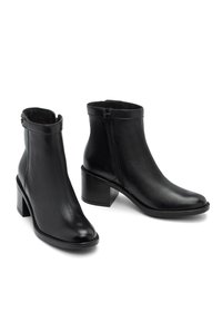 Stivali alla caviglia in pelle nera con una texture liscia, punta affusolata e tacco a blocco. Presentano una zip laterale e un dettaglio di risvolto decorativo.