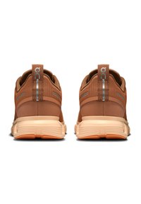Baskets de sport marron en matériaux mesh et caoutchouc, avec une semelle texturée et des accents réfléchissants ; la vue arrière montre des languettes de tirage.