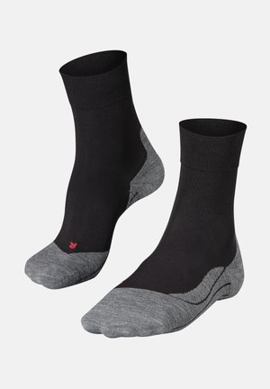 Paar schwarze Knöchelsocken mit grauen Zehen- und Fersenbereichen, mit einem kleinen roten Buchstaben „R“ auf dem Zehenbereich der rechten Socke.