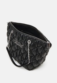Bolso de mano de cuero negro acolchado con cadena de plata y correa de hombro de cuero. Presenta un cierre superior con cremallera y un logotipo distintivo en la parte frontal.