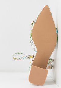 Chaussure à talon haut à motif floral avec un tissu blanc, un bout pointu et une semelle beige clair. Comprend des lacets pour un maintien sécurisé.