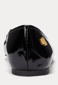 Μαύρες παπούτσια μπαallet με γυαλιστερή δερματίνη, με στρογγυλή μύτη, που διαθέτουν μια μικρή χρυσή λογότυπη λεπτομέρεια στο πλάι και επίπεδη σόλα. Λείος, γυαλιστερός υφιστάμενος.