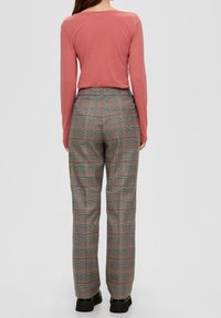 Topp med långa ärmar i rosafärg och grå rutiga byxor med orangea accenter, med en avslappnad passform och rak bendesign.