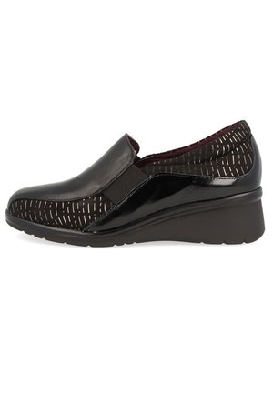 Zapato negro tipo slip-on con la punta de charol brillante, panel lateral elástico y parte superior de tela texturizada con patrones lineales dorados. Tacón cuña.