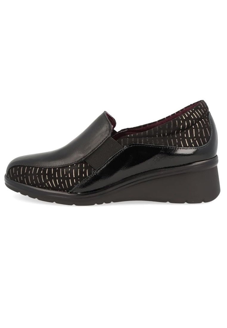 Zapatos negros tipo slip-on con punta de cuero liso y parte superior de tela texturizada con patrones y acentos metálicos; suela de cuña de goma.