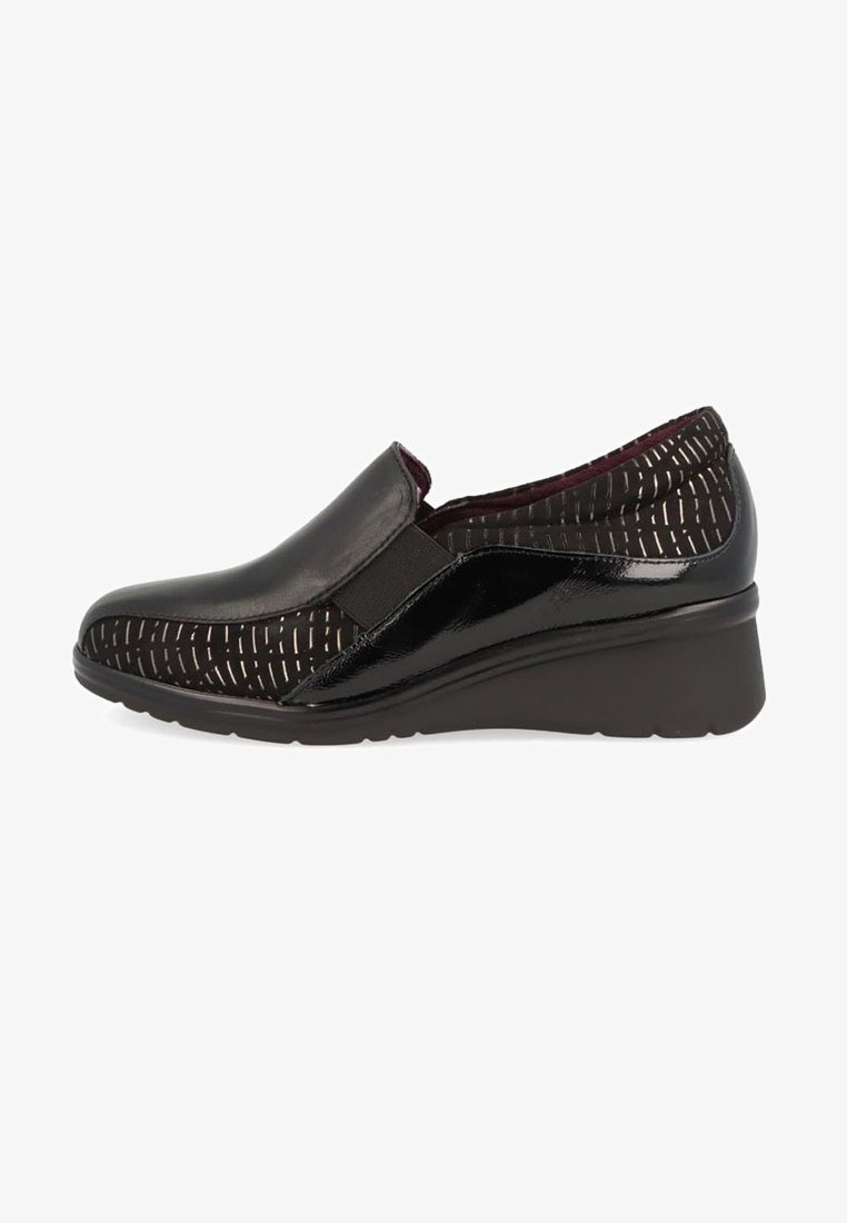 Zapatos negros tipo slip-on con punta de cuero liso y parte superior de tela texturizada con patrones y acentos metálicos; suela de cuña de goma.