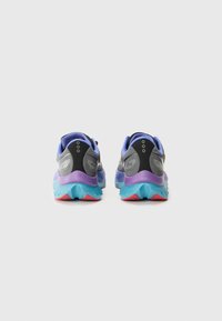 Des chaussures de course avec une tige violette et grise, rehaussée d'un talon noir texturé, et une semelle multicolore en bleu clair et rouge.