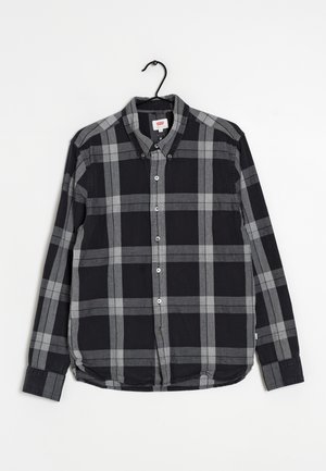 Camicia a maniche lunghe a quadri in nero e grigio, con colletto abbottonato, bottoni frontali e orlo curvo. Realizzata in tessuto intrecciato.