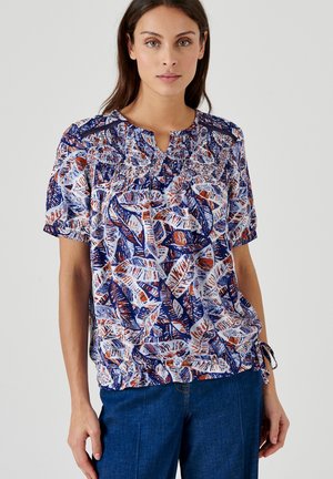 T-shirt à manches courtes en bleu, blanc et orange avec un motif de feuilles. Présente des fronces au col et un ourlet à cordon pour plus de forme.