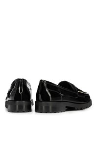 Schwarze Lacklederloafers mit einer niedrigen, strukturierten Sohle, verziert mit dekorativen goldenen Akzenten an der Vorderseite und glatter Oberfläche.