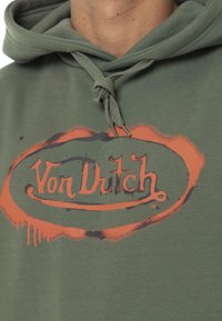 Hoodie vert olive arborant un graphique noir et orange de Von Dutch, avec une capuche à cordon et un intérieur en polaire texturée.