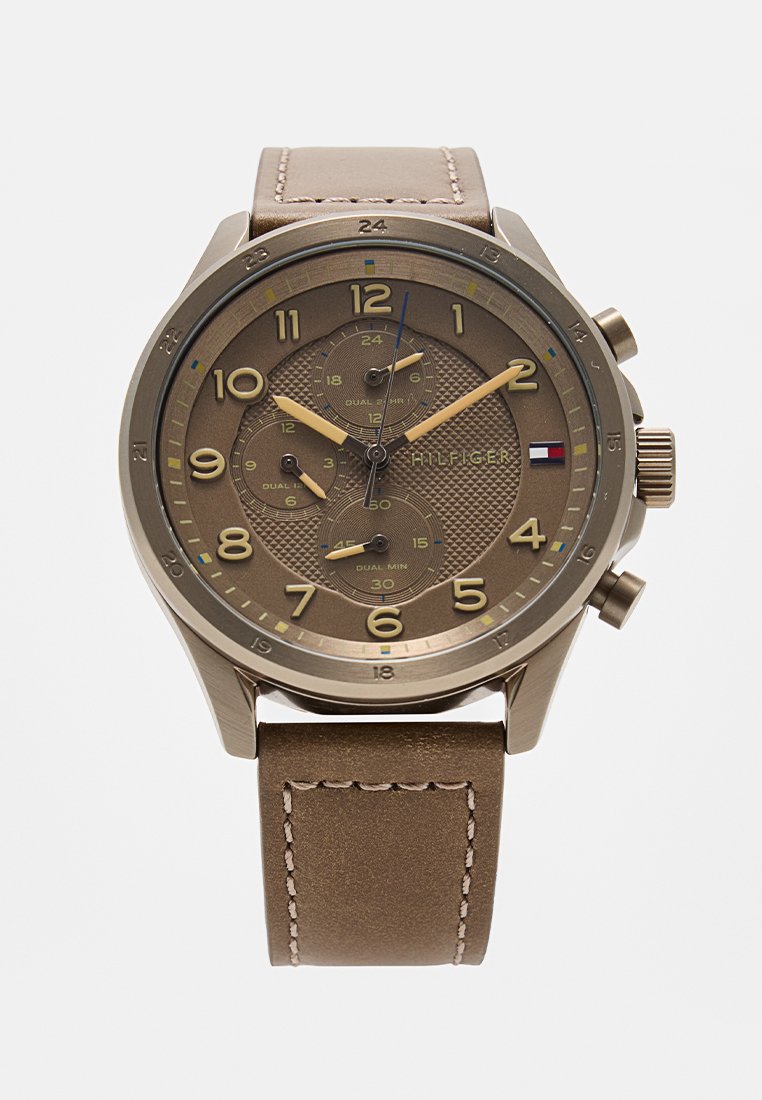 Brązowy zegarek chronograf z fakturowaną tarczą, dużymi cyframi i funkcjami stopera. Skórzany pasek z detalami przeszycia. Metalowe akcenty.