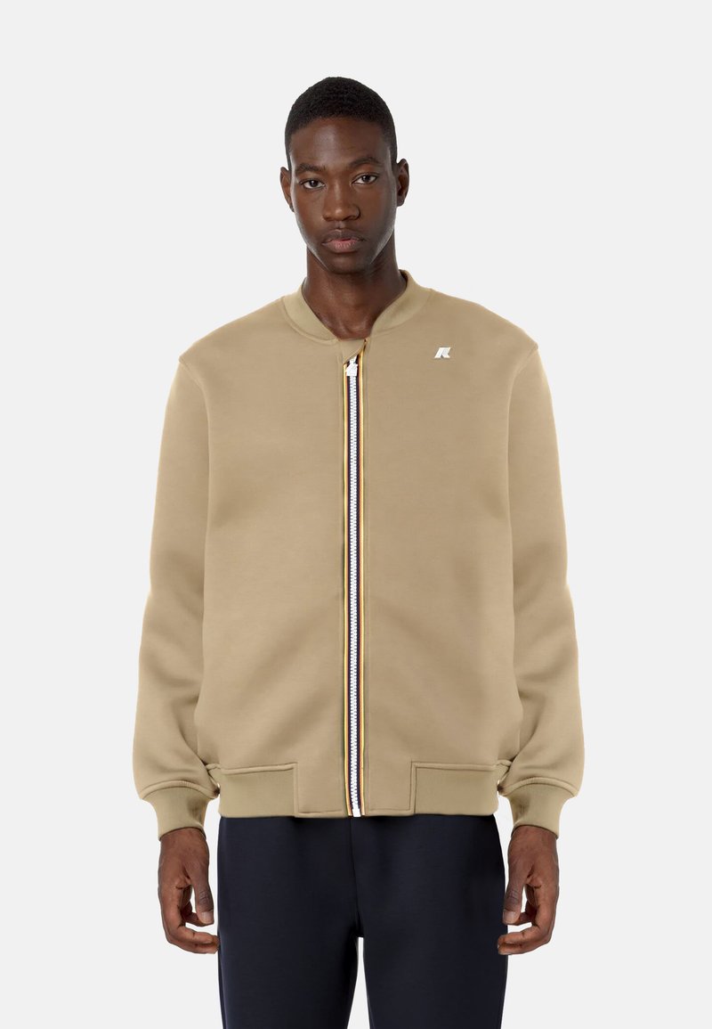 Giacca bomber khaki con zip frontale, polsini e orlo a costine, dotata di un piccolo logo sul petto e dettagli con zip a strisce multicolori.