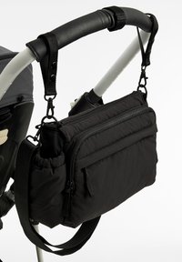 Črna torba za ramo iz mehke tkanine, z več žepki z zadrgo in nastavljivim trakom, pritrjena na ročaj otroškega vozička.