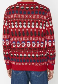 Red knitted sweater with holiday motifs, featuring snowmen, trees, gifts, and Santa faces, textured fabric, ribbed cuffs, and hem.
