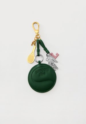 Llavero Lacoste de cuero verde con logo de cocodrilo en relieve, colgante de raqueta de tenis dorada, colgante de cocodrilo plateado y colgante rosa con la letra F.