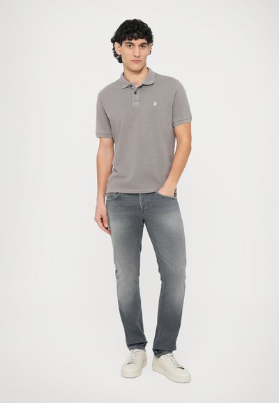 Γκρι πόλο μπλουζάκι με γιακά και τρία κουμπιά· συνδυασμένο με ψηλόμεσα γκρι τζιν και λευκά αθλητικά παπούτσια. Απλός σχεδιασμός και casual εμφάνιση.