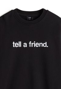 Sort sweatshirt med rund halsudskæring, prydet med hvid tekst, der siger "fortæl en ven" tværs over brystet. Blød stofstruktur.