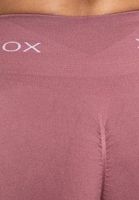 Roze legging met een textuur tailleband. Heeft een gestikte middennaad voor vorm en elasticiteit. Merklogo aan de bovenkant.