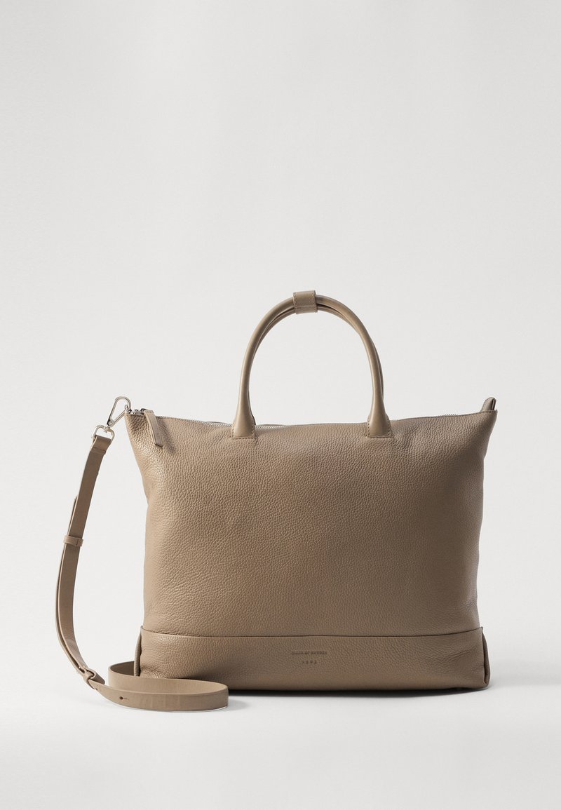 Tan krāsas ādas soma ar teksturētu apdari, divām augšējām rokturiem un noņemamu plecu siksnu, rāvējslēdzēja aizdari un minimālistisku dizainu.