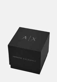 Mustast kardboonist kast, mille peal on kõrgendatud hõbedane "A/X" logo ning külgedel tekst "ARMANI EXCHANGE".