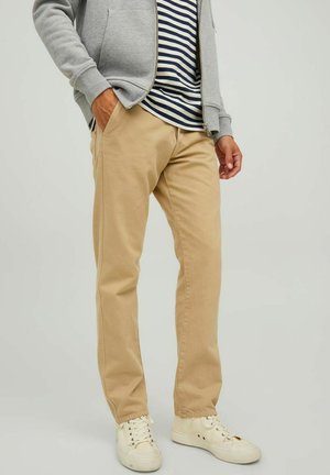 Beige cotton pants with a straight cut, worn with a grey zip-up hoodie and navy-striped T-shirt, paired with white sneakers.